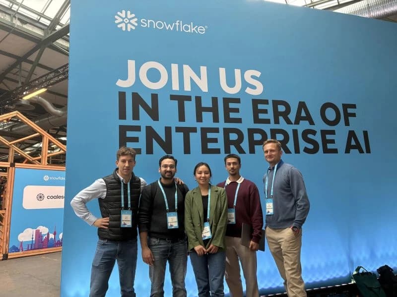 Five DATANOMIQ colleagues at a technology conference, in front of an event backdrop.