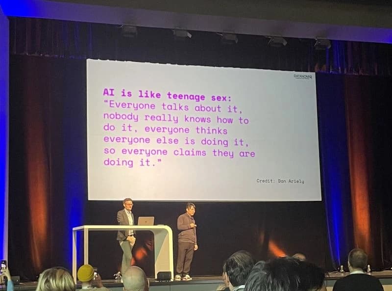 DATANOMIQ speakers on stage at an event, presenting in front of a slide on AI.